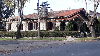 A full stone-cladded chalet with a rectangular, long layout and "embedded" portico-style porch