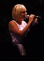 A blonde woman wearing a white dress is performing